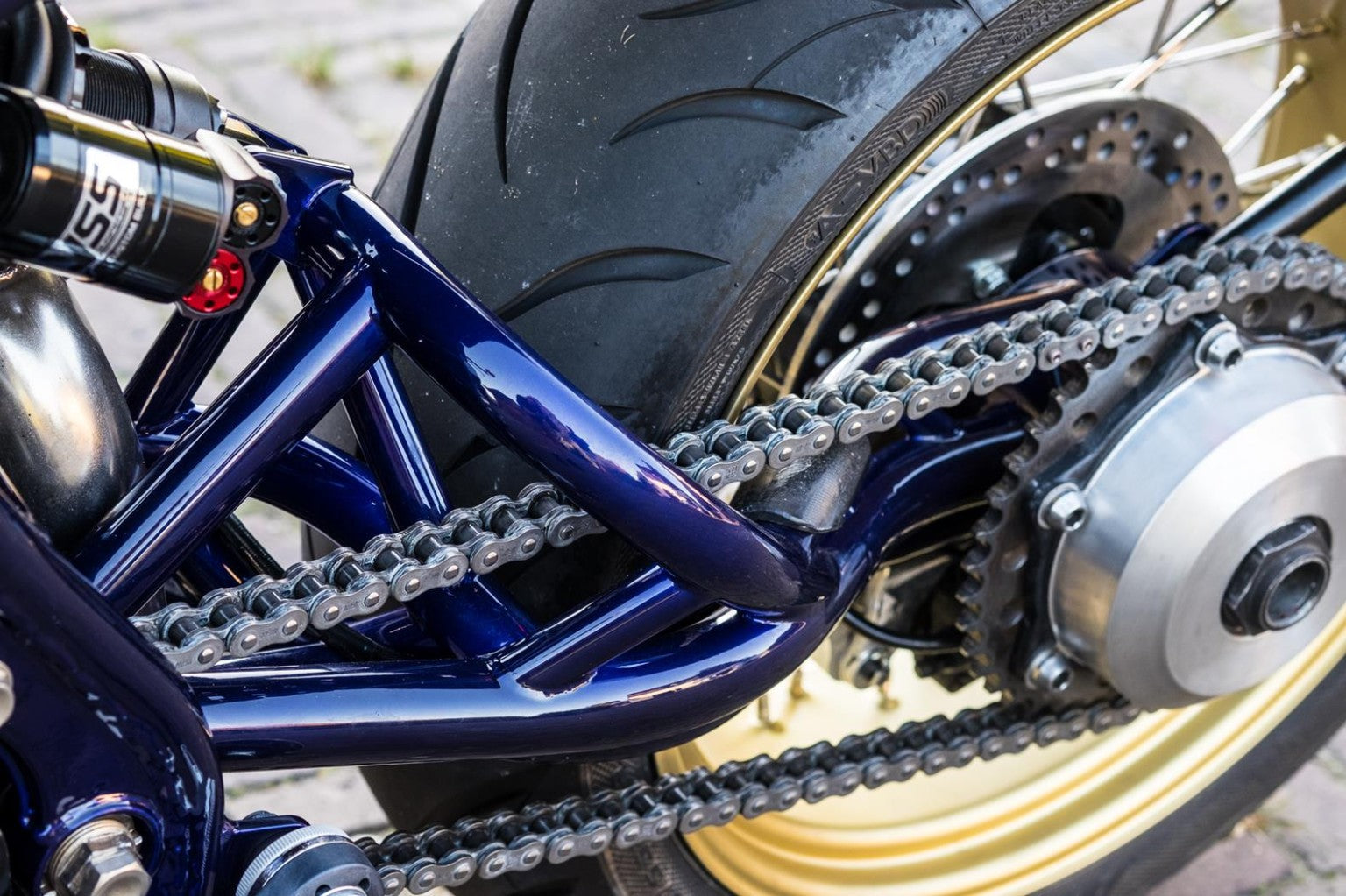 Close-up of a Vanta custom bike rear wheel, chain, and metallic blue frame.
