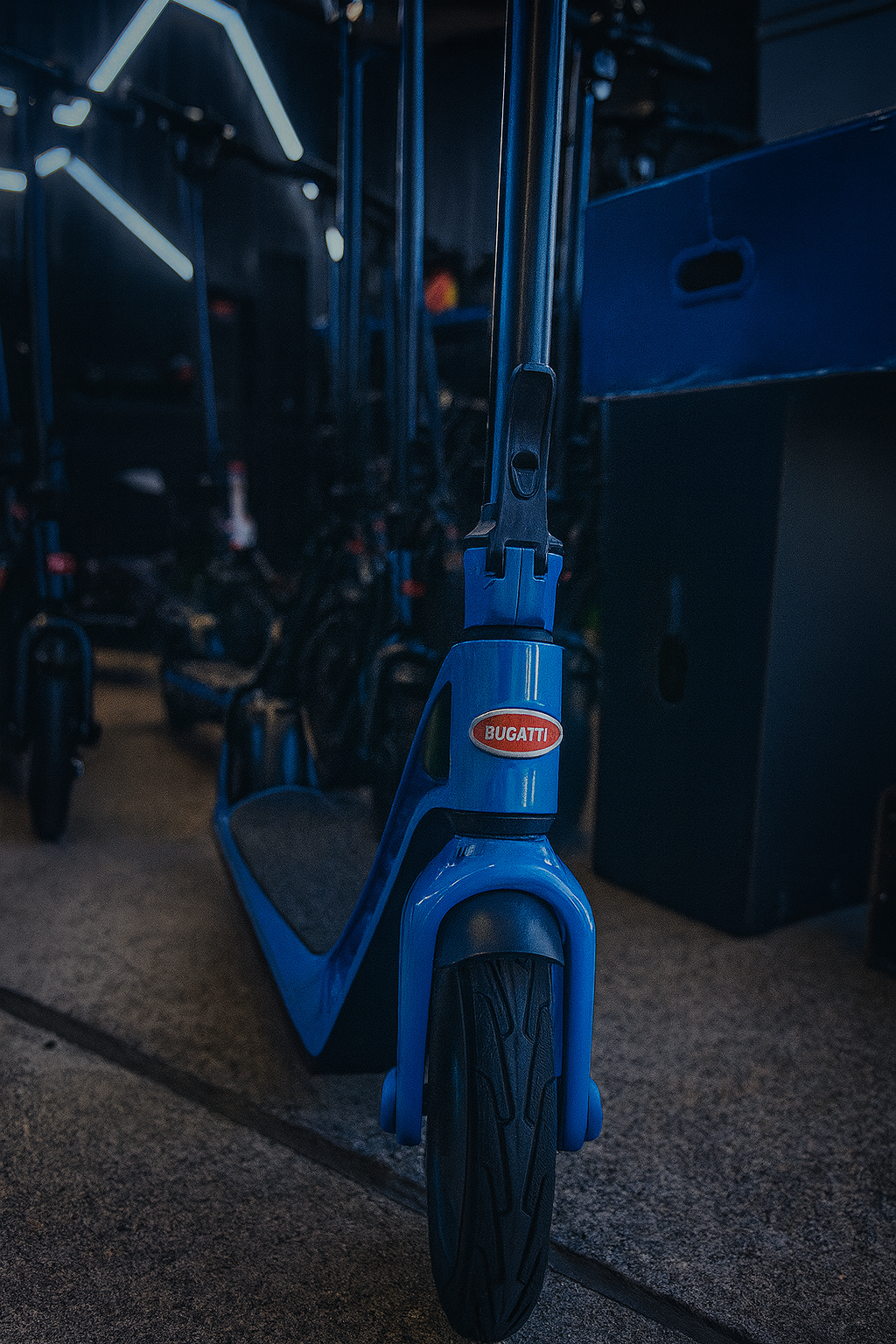 Blue scooter with Bugatti logo in a dark indoor setting